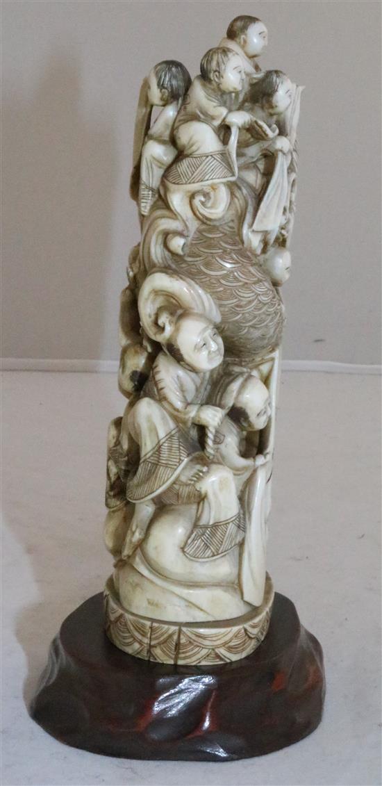 A Japanese walrus ivory okimono of men holding a giant carp, early 20th century, 15cm, wood stand